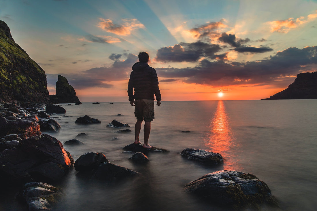 Man standing on beach looking at sunset