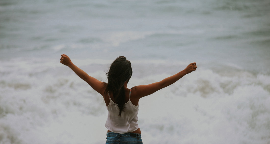 woman in front of ocean with outstretched arms