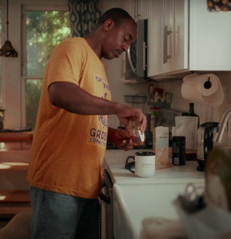 
  Man in kitchen adding honey to a mug of mud water
